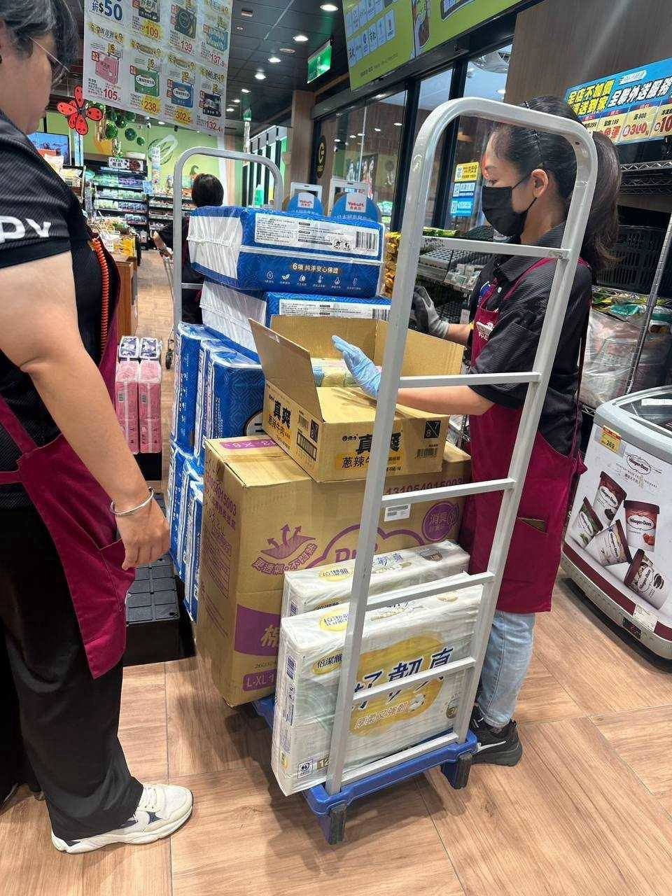 夥伴在商店裡整理推車上的紙箱與日用品