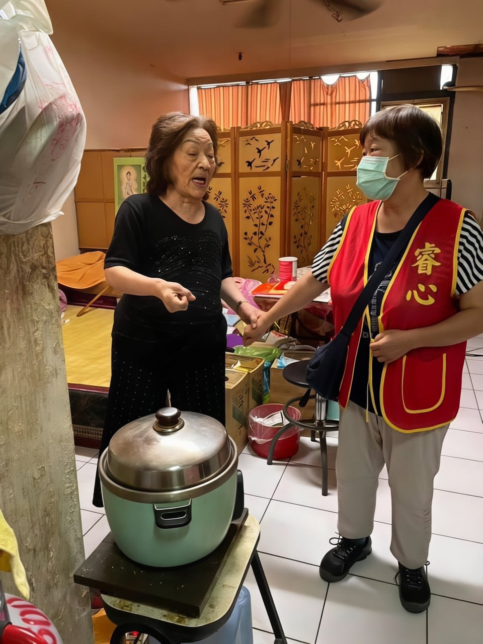 穿紅色背心的志工與長者握手交談
